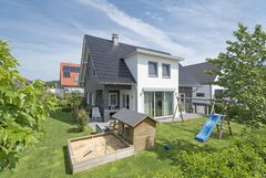Gartenansicht mit Blick auf die überbaute Terrasse des Holzhauses Ellerbeck