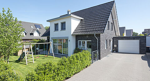 Außenansicht des Holzhauses Ellerbeck mit Einfahrt zur Garage - zmh.com